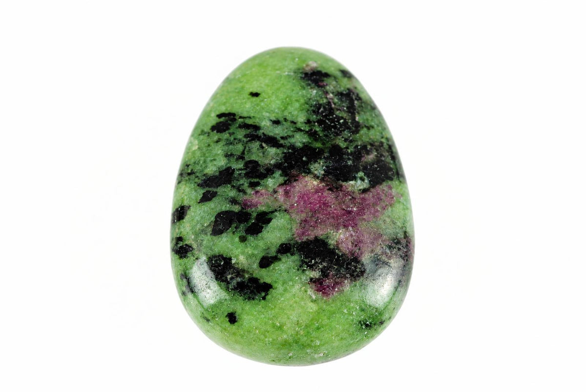 A polished, oval-shaped stone with a green base, black speckles, and pink patches on a white background.