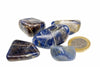 Five polished blue stones with white and brown veins, arranged on a white surface next to a one-euro coin.