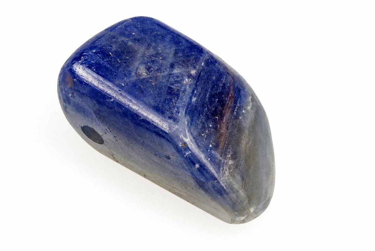 A polished, deep blue sapphire pendant with a smooth, rounded shape and visible surface texture on a white background.