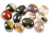 A collection of polished, multi-coloured sardonyx stones with bands of red, black, white and brown on a pale surface.