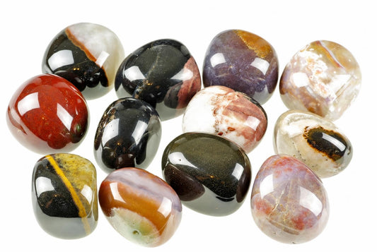 A collection of polished, multi-coloured sardonyx stones with bands of red, black, white and brown on a pale surface.