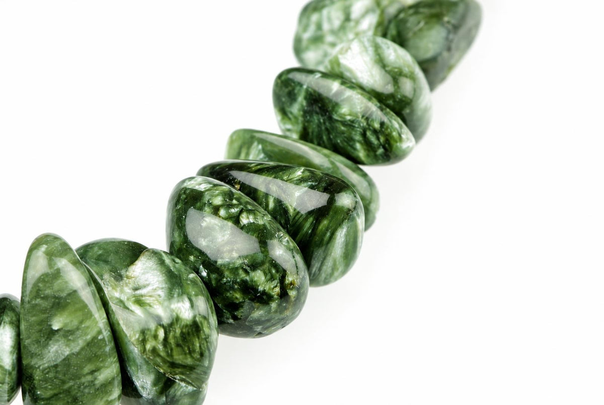 A string of polished, oval-shaped beads with green and white swirling patterns on a pale surface.