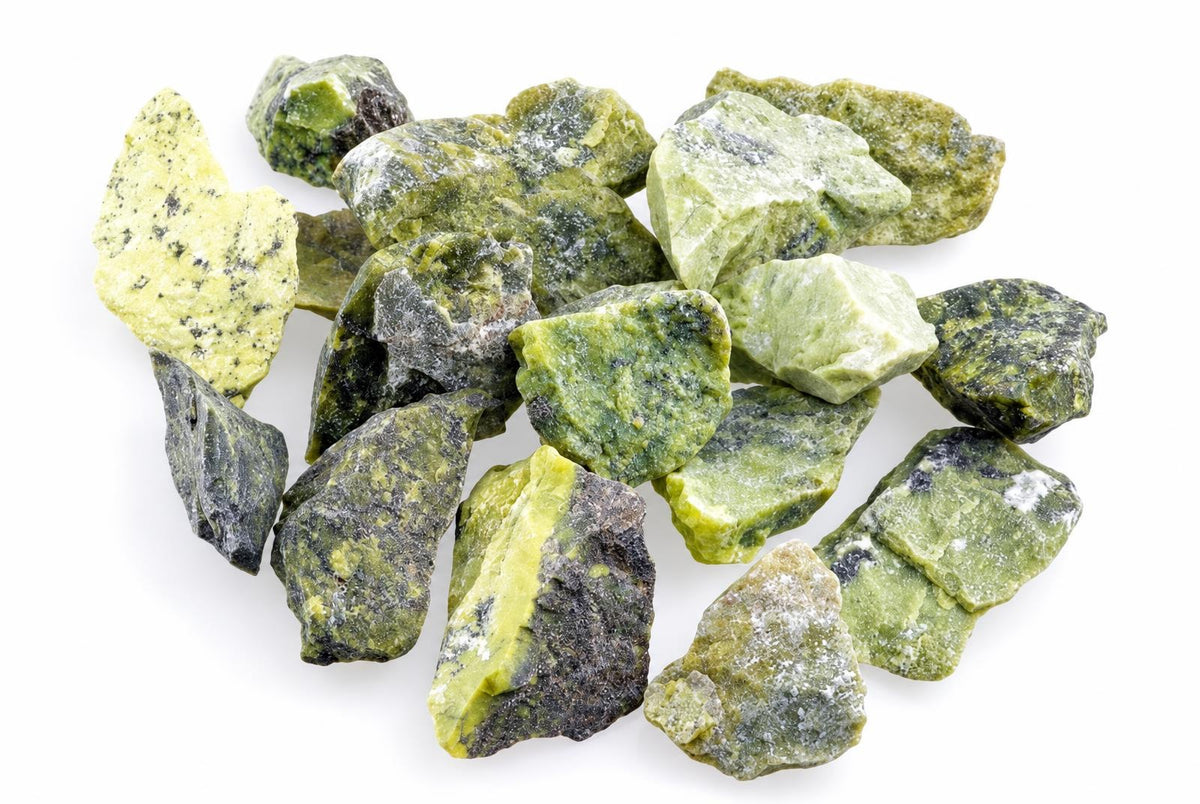 A pile of raw Serpentinite stones in various shades of green, yellow and dark grey on a white background.