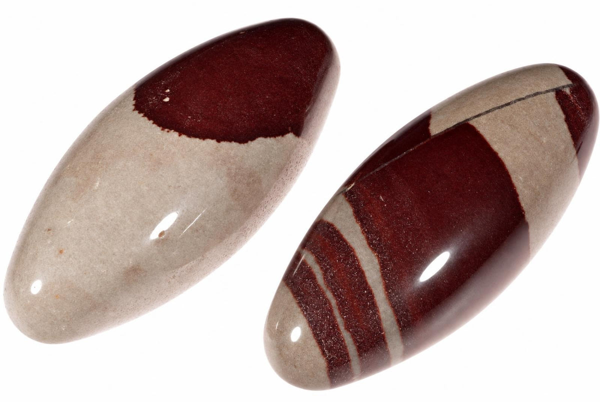 Two polished, oval-shaped stones with smooth surfaces. One is cream and dark red; the other has striped bands of cream and dark red on a white background.