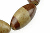 A close-up of a bracelet with oval beads in dark brown and pale greenish-grey, set against a white background.