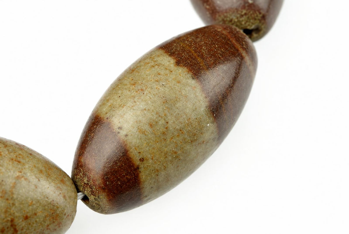 A close-up of a bracelet with oval beads in dark brown and pale greenish-grey, set against a white background.