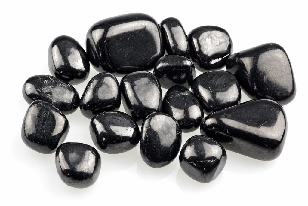 Smooth black stones with rounded irregular shapes and bright surface reflections are grouped on white.