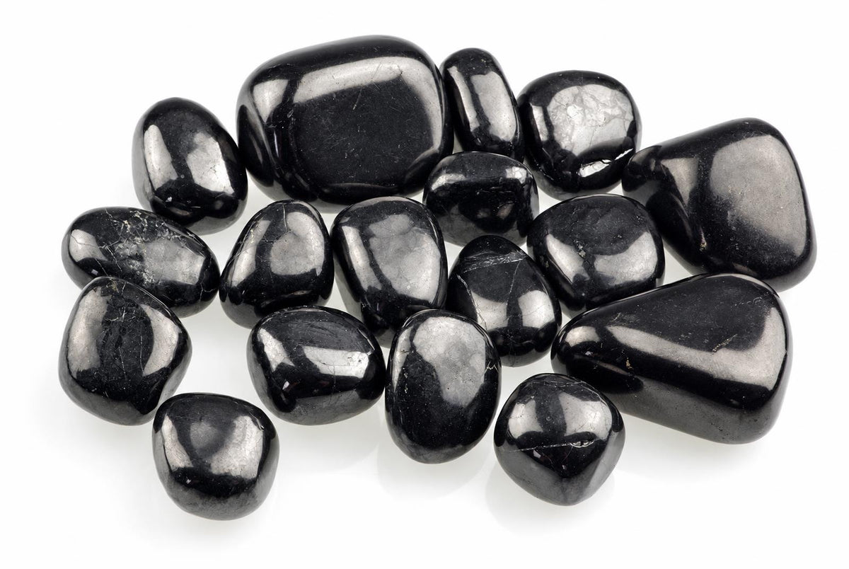 Smooth black stones with rounded irregular shapes and bright surface reflections are grouped on white.