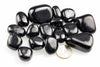 Smooth rounded black stones with bright reflections rest on a white background beside a euro coin.