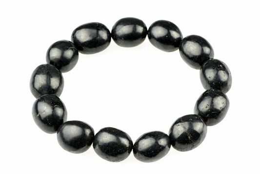 A bracelet of smooth glossy black oval beads forms a circle on a white background.