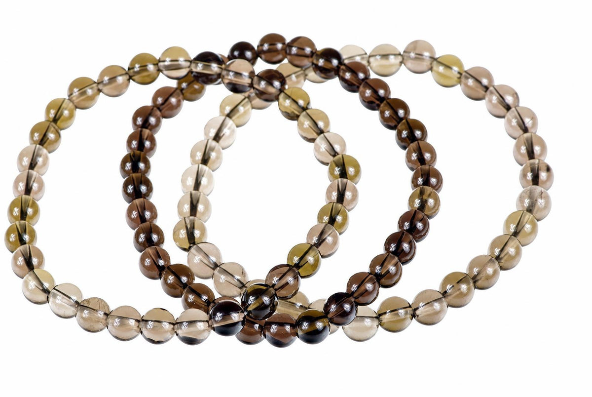 A bracelet made of round, translucent beads in shades of brown, tan and black on a white background.