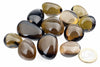 A group of polished, smooth stones in dark brown and black tones on a white surface with a one-euro coin for scale.