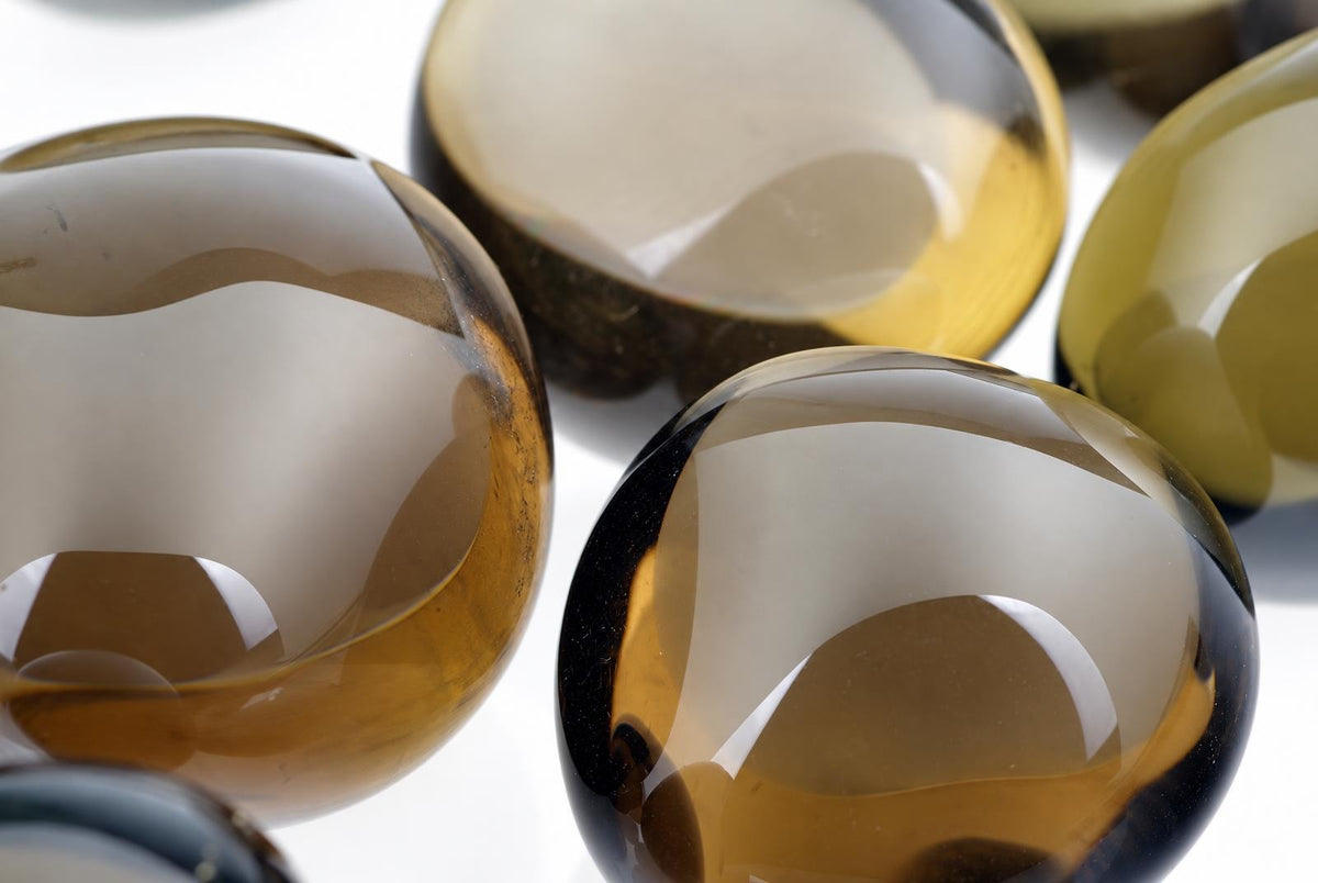 Several polished, translucent spheres of smoke quartz rest on a pale surface.