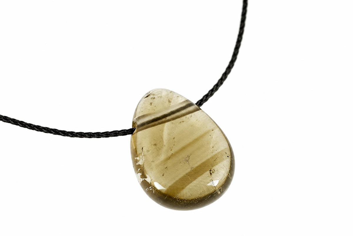 A teardrop-shaped pendant with a translucent, golden-brown stone featuring dark diagonal bands, set on a black cord against a white background.