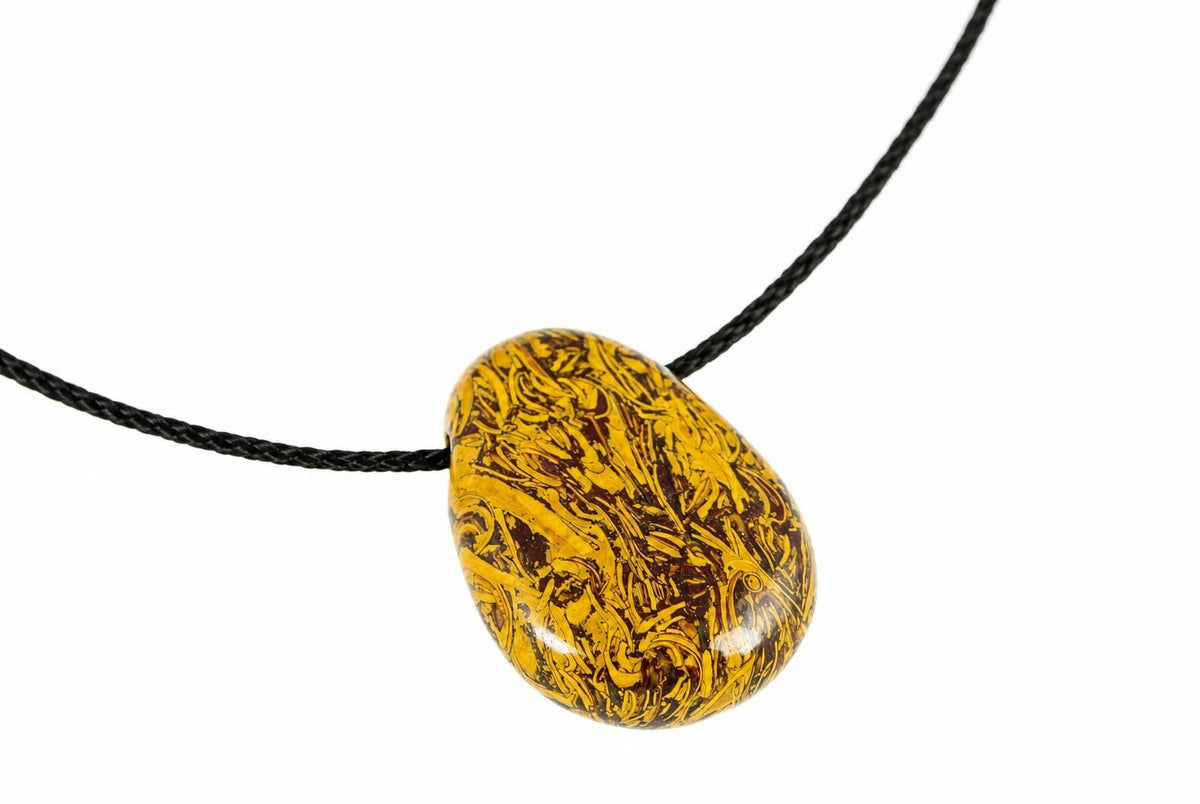 A polished, teardrop-shaped pendant with a snakeskin jasper pattern of yellow and dark brown swirls on a black cord against a white background.