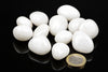 A group of smooth, white stones on a dark surface with a one-euro coin for scale.