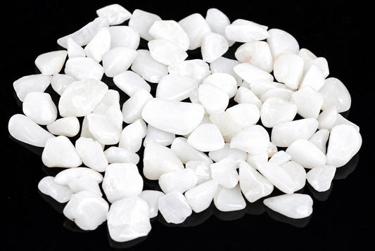 A pile of small, smooth white stones on a dark surface.