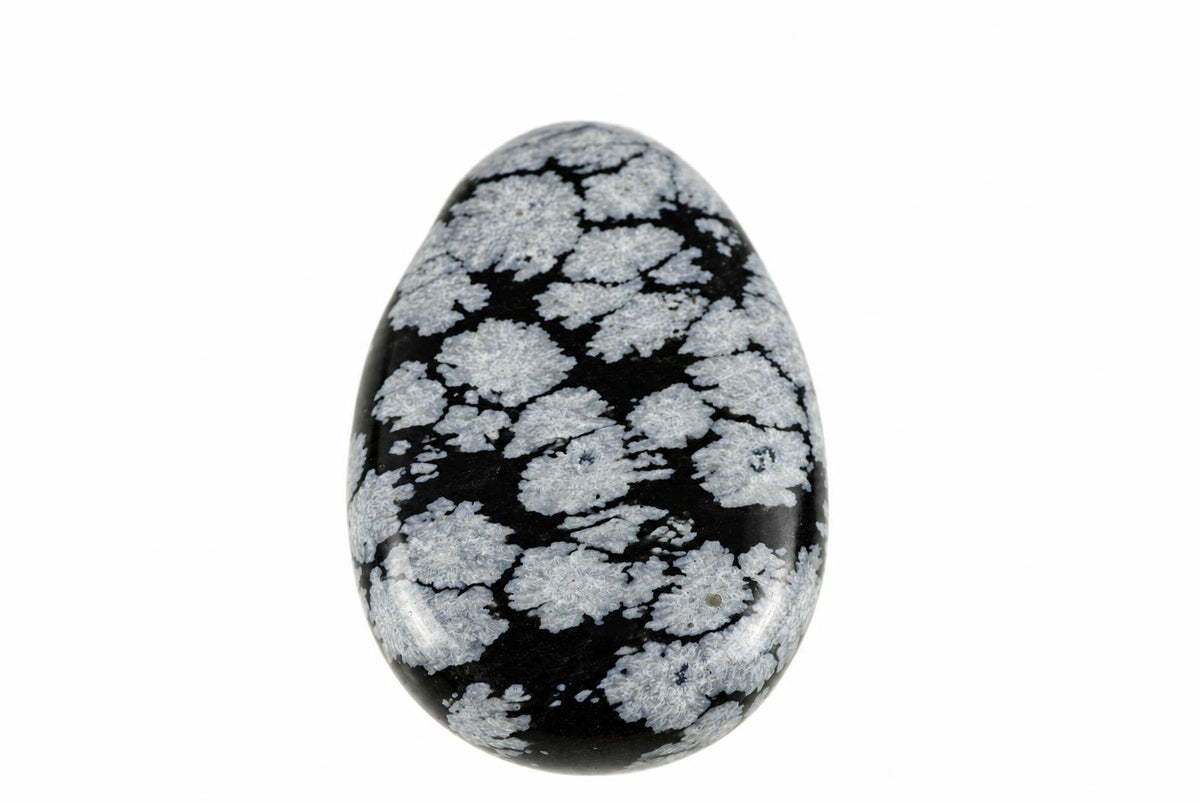 A polished, egg-shaped stone with a black background and white snowflake patterns on a plain surface.