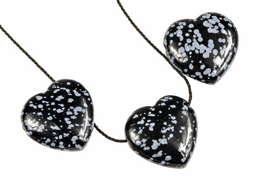Three glossy black heart-shaped pendants with white speckles hang from a dark cord against a plain background.