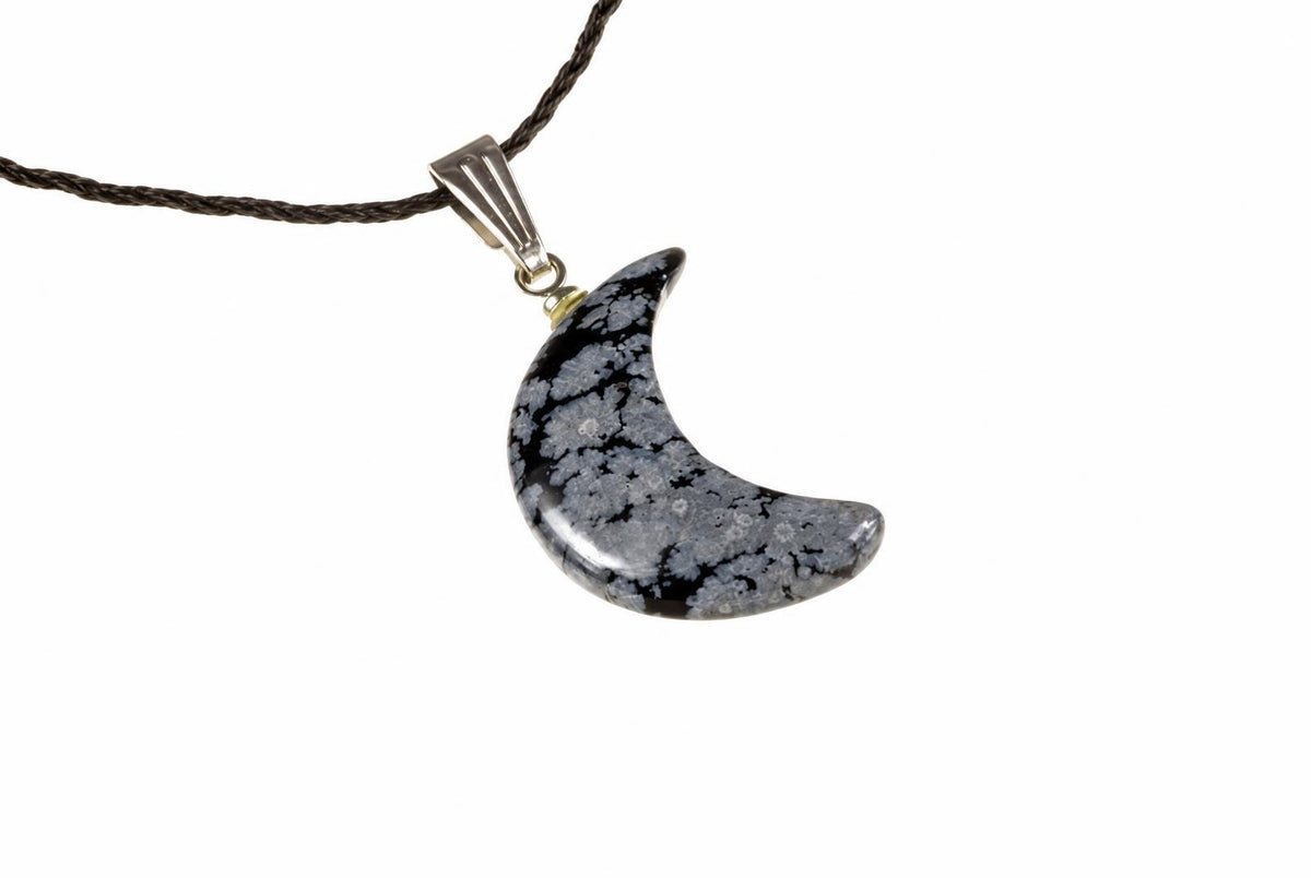 A crescent-shaped pendant with a black and white speckled stone, attached to a dark cord via a silver-toned bail.