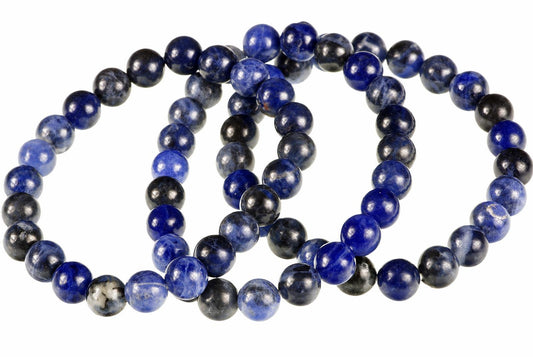 A coiled bracelet of round beads in dark blue, black and grey tones on a white surface.