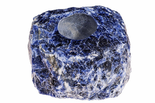 A rough, blue and white sodalite stone with a circular hole in the top, set against a white background.