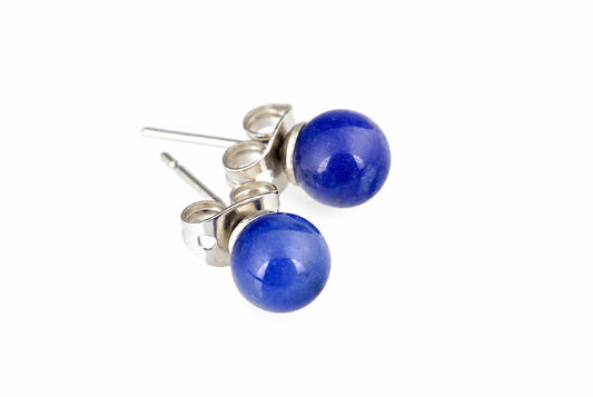 A pair of stud earrings with round dark blue sodalite beads and silver-toned posts on a white surface.