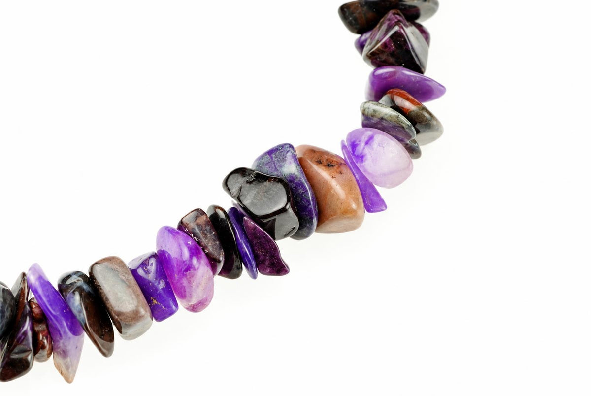 A bracelet made of polished chip beads in purple, black, brown and grey tones on a white background.