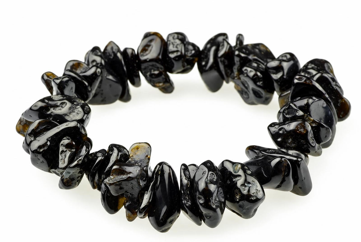 A bracelet made of irregular, glossy black beads with brown and silver-toned inclusions on a white surface.
