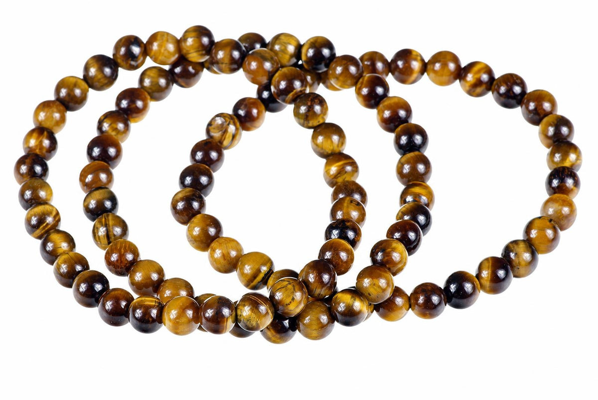 Overlapping bracelets of glossy round beads with golden-brown and dark bands lie on a white background.