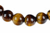 A row of round beads with brown and golden tiger eye stripes, glossy finish, on a white background.