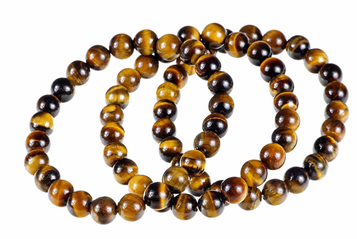 Overlapping loops of glossy round golden-brown and dark beads rest on a white surface.