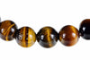 A row of round tiger eye beads with golden brown and black stripes on a white background.