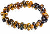 A bracelet of glossy curved beads with golden-brown and dark bands forms a ring on a white background.