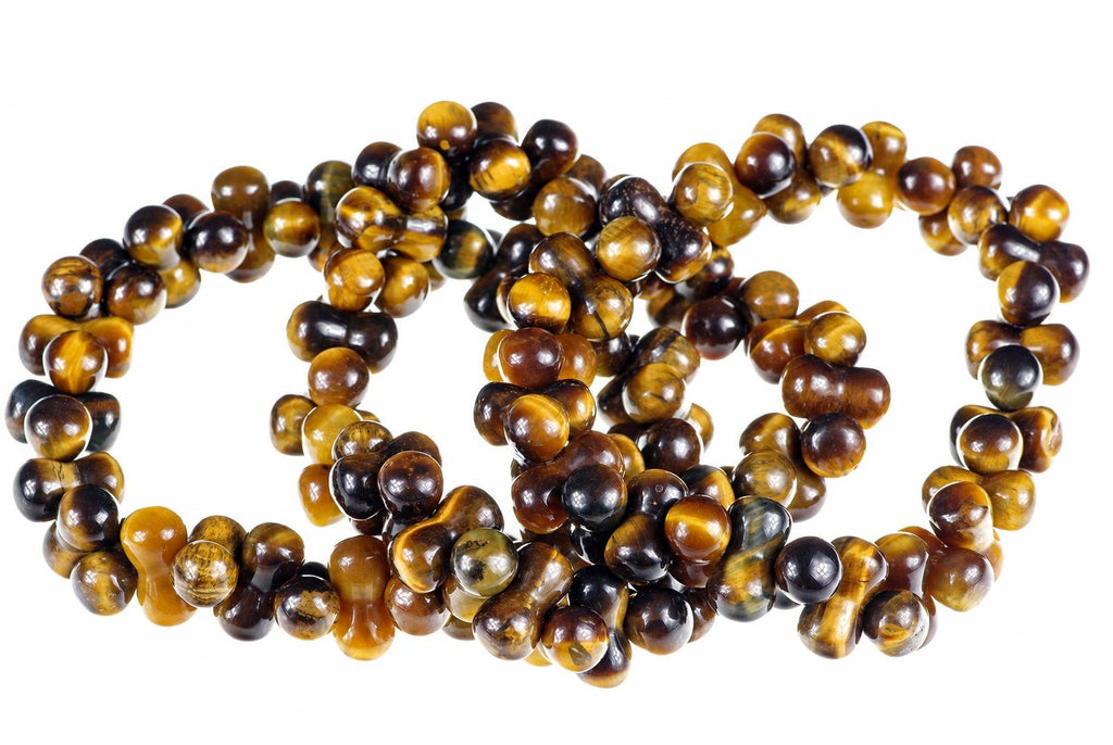 Overlapping bracelets of glossy curved beads in golden-brown and dark tones lie on a white background.