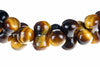 A bracelet of polished beads with golden brown and black stripes, arranged in a row on a white surface.