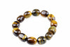 A bracelet made of polished oval beads with dark brown and golden-yellow tiger eye patterns on a white background.