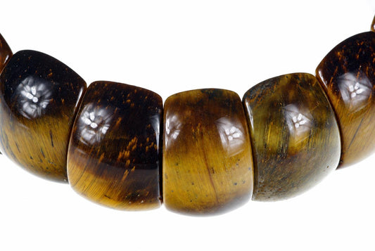 A bracelet with large, polished beads showing tiger eye patterns in dark brown and golden yellow tones against a white background.