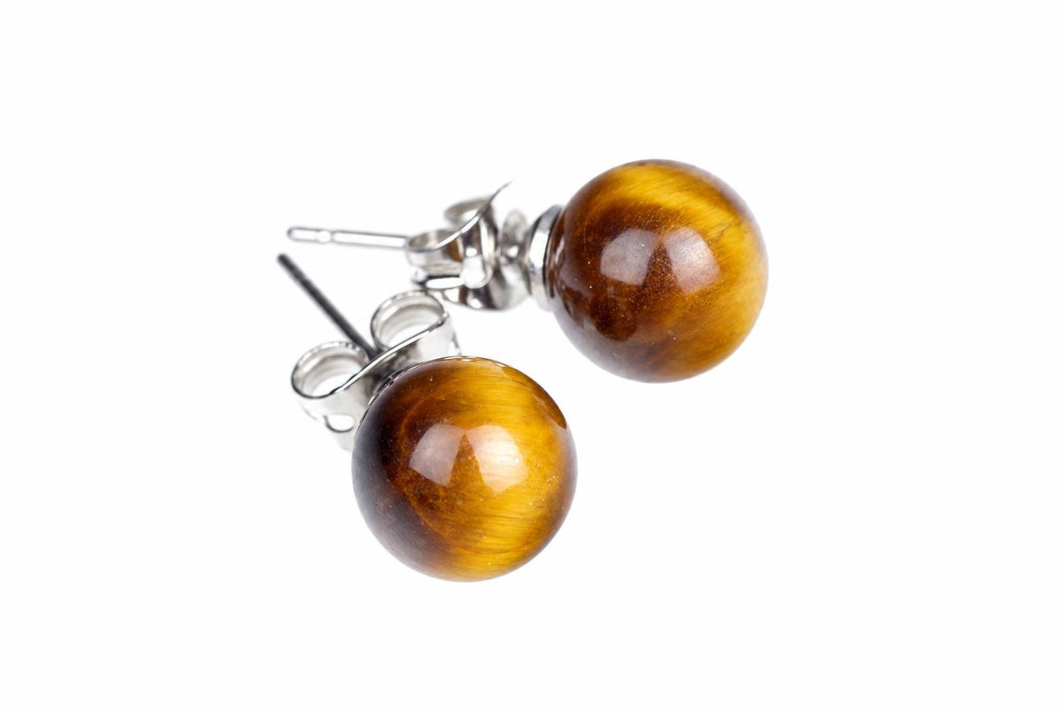 Two glossy round golden-brown stud earrings with silvery posts and butterfly backs rest on white.