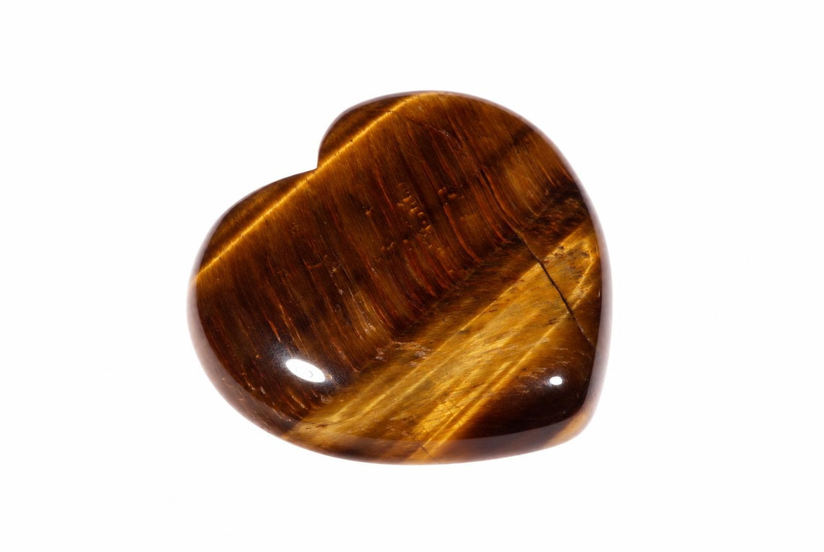 A polished heart-shaped tiger eye stone with golden-brown stripes and a smooth surface on a white background.