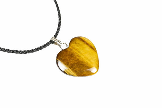 A heart-shaped tiger eye pendant with golden-brown stripes hangs from a dark braided cord against a white background.