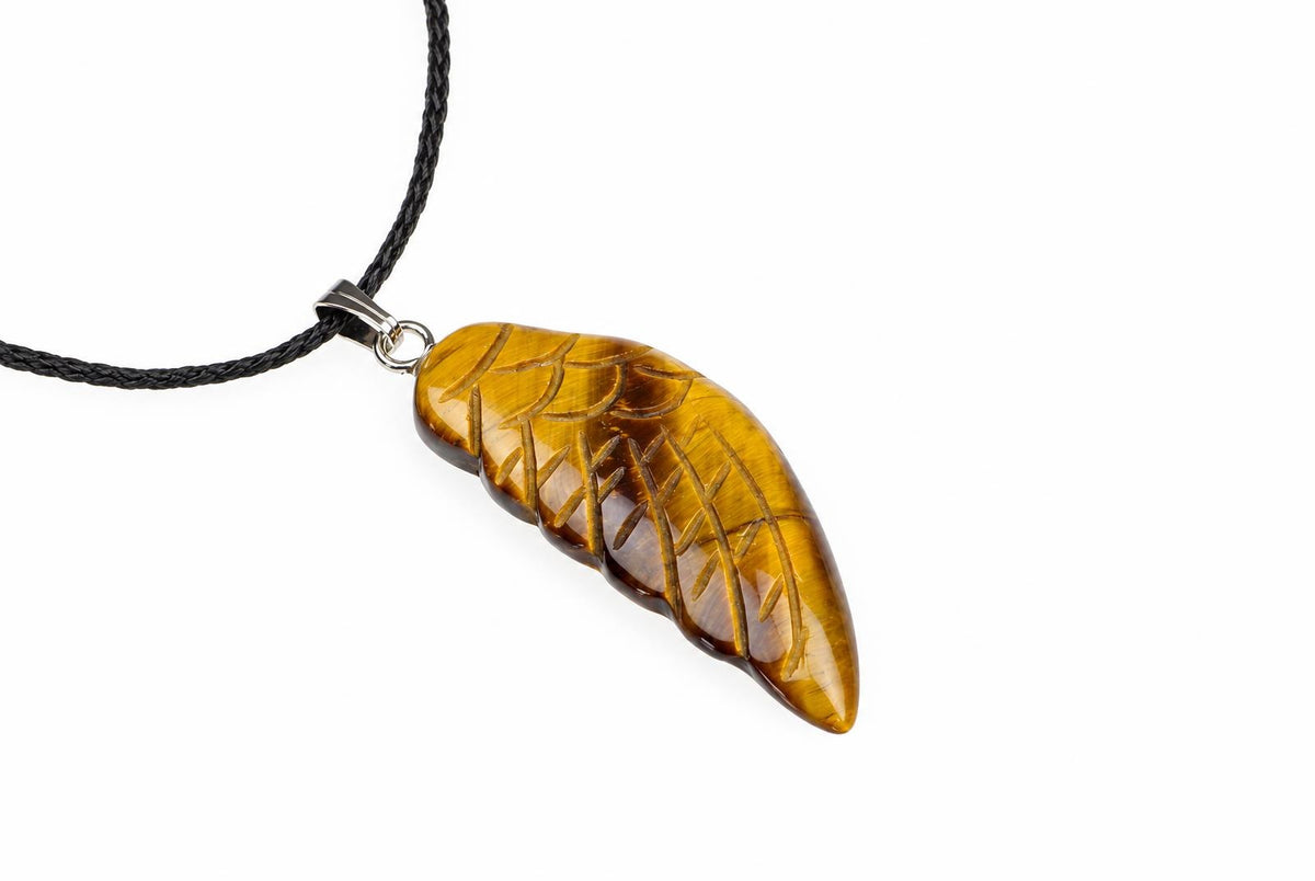 A yellow-brown leaf-shaped pendant with carved vein details hangs from a black cord on a white background.