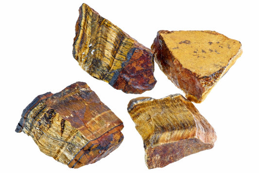 Four raw tiger eye mineral specimens with golden brown and black banding on a white background.