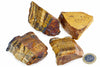 Four pieces of raw tiger eye mineral with golden brown and black banding, arranged on a white surface next to a one euro coin.