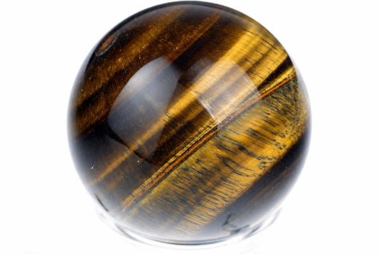 A polished tiger eye sphere with golden and dark brown stripes, resting on a clear base against a white background.