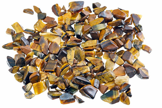 A pile of small tiger eye pieces shows golden brown bands and dark polished faces against a plain white background.