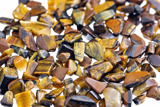 A pile of small, polished tiger eye stones with golden brown and black stripes on a white background.