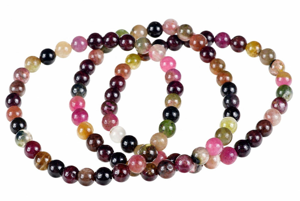 A multi-coloured beaded bracelet with round beads in pink, green, black, brown and white on a pale surface.