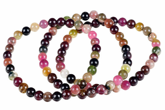 A multi-coloured beaded bracelet with round beads in pink, green, black, brown and white on a pale surface.