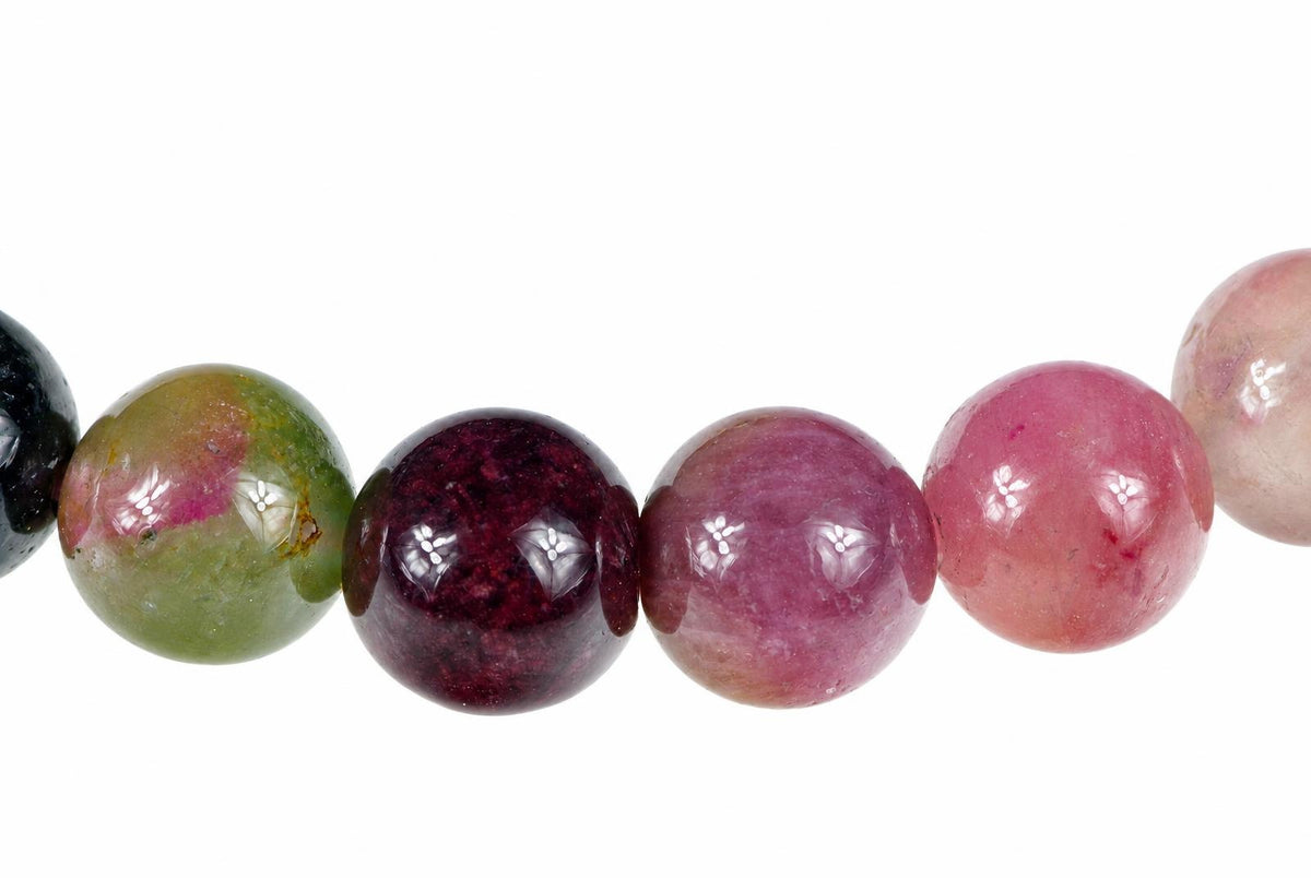 A row of round, polished tourmaline beads in green, dark red, pink and pale tones on a white background.